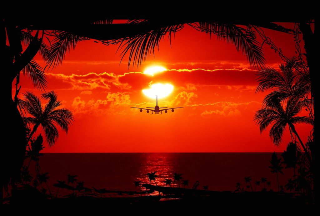 Plane flying low over the sea during the sunset.