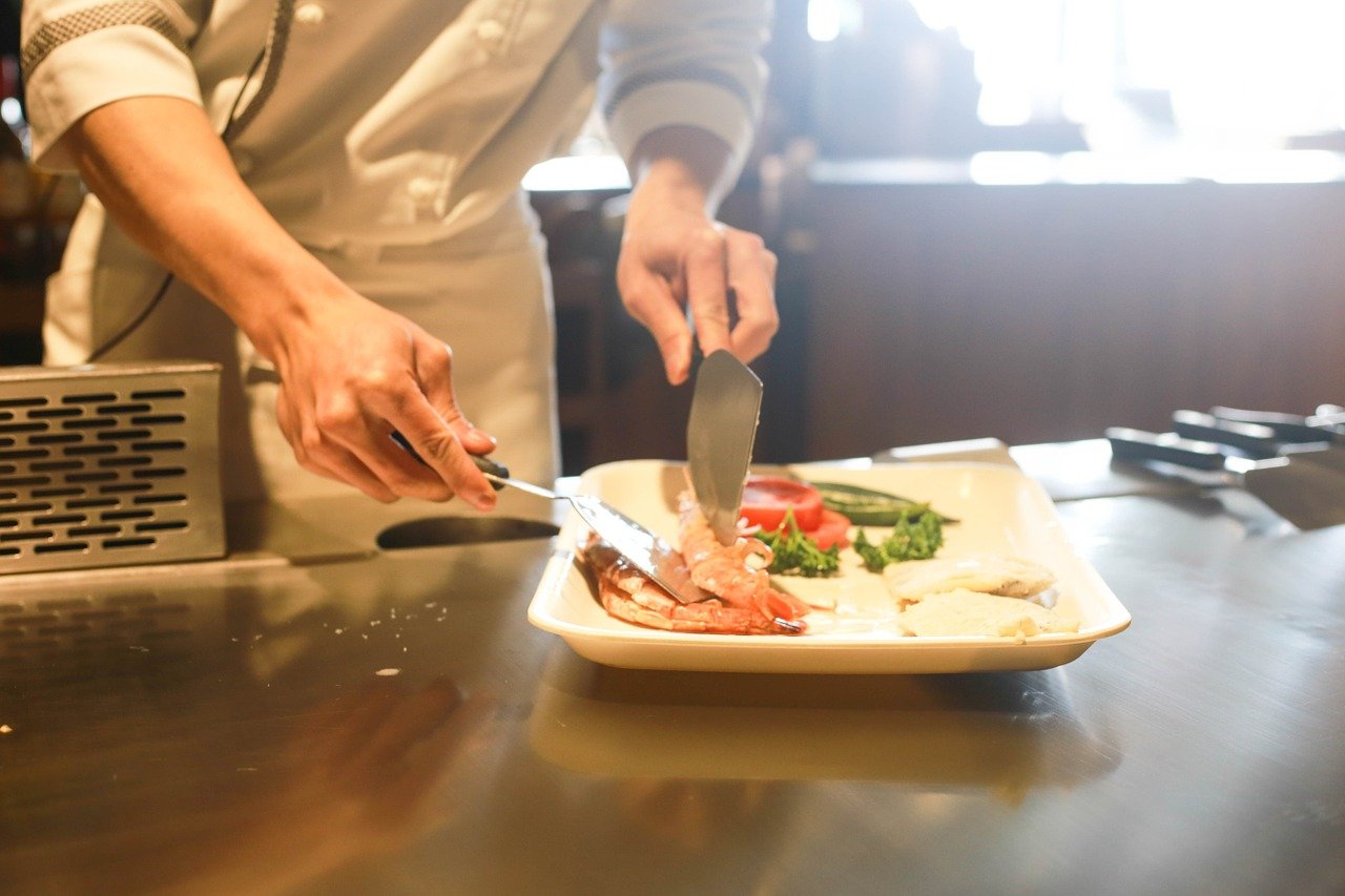 A private chef serving seafood onto a plate of salad.